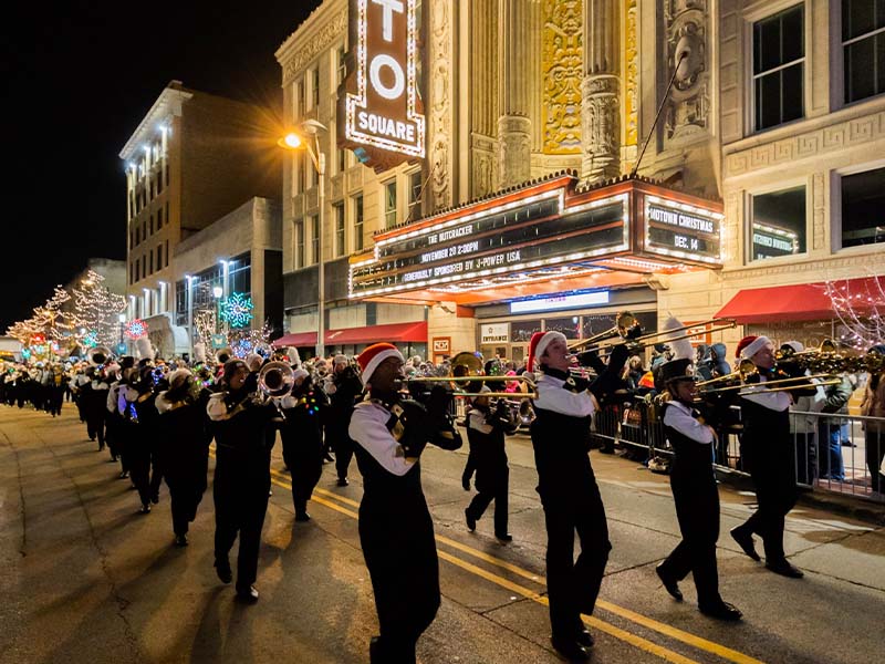 Band marching in front of the Rialto Marguee