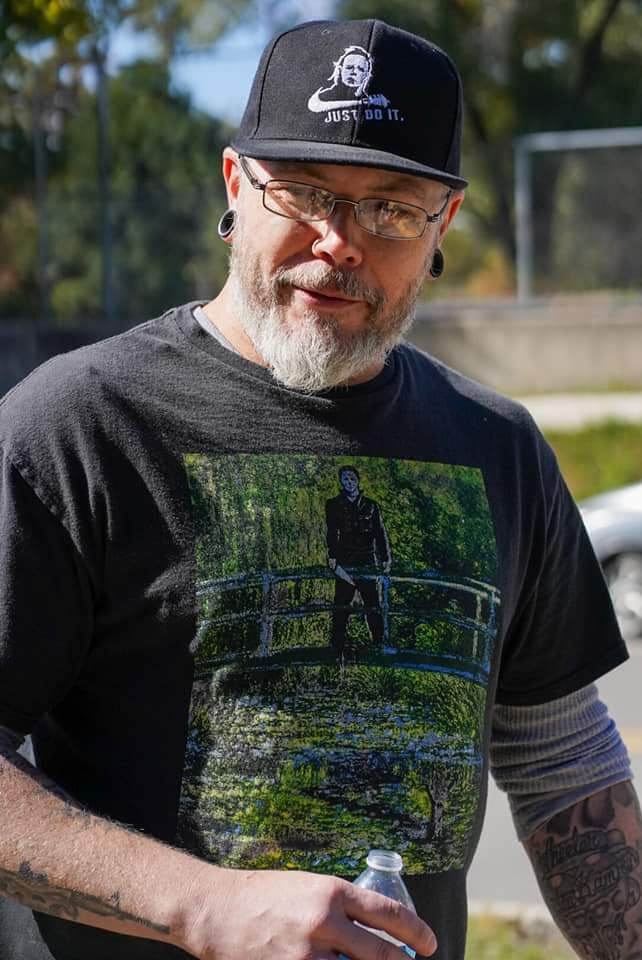 Man in a black t-shirt and black baseball cap with a beard