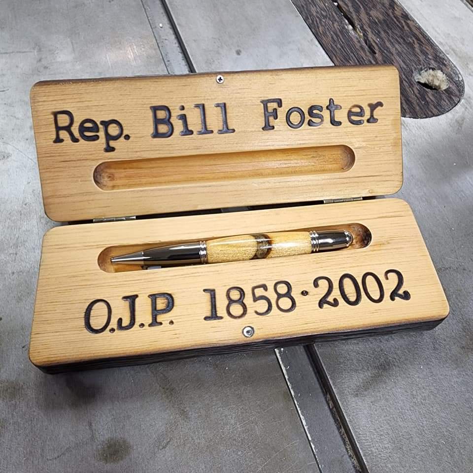 Wooden pen case holding a wooden pen with Rep. Bill Foster O.J.P. 1858-2002 engraved