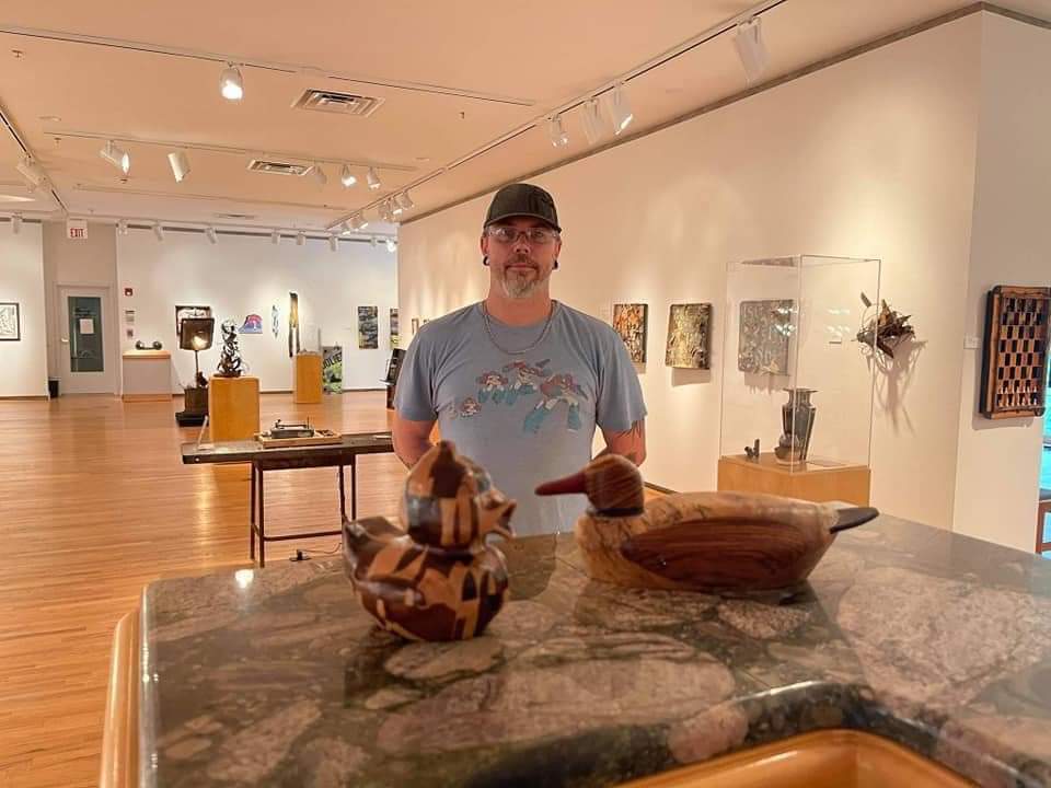 Two wooden ducks with man in an art gallery