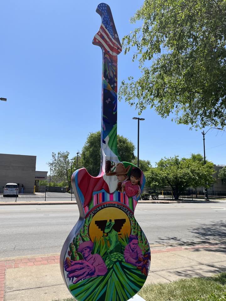 Guitar statue man with a hat and sunset painted on it