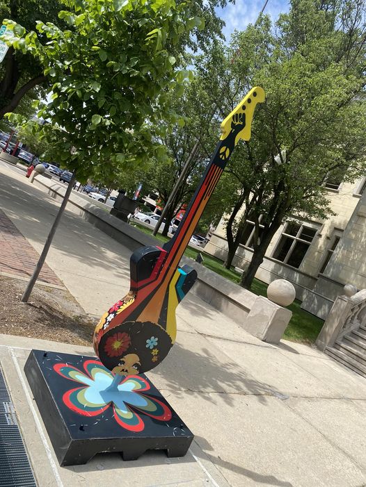 Guitar statue with woman with natural hair into flowers