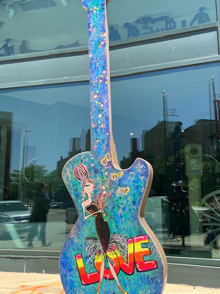 Guitar statue with woman singing painted on it