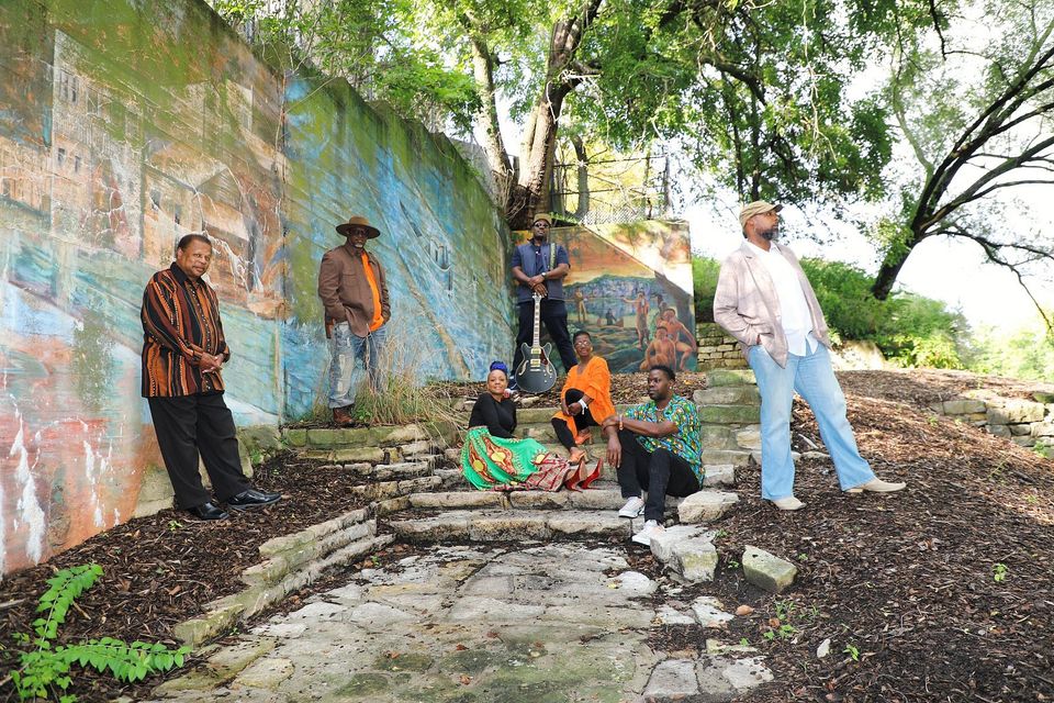 Group of people artistically posed on rocks with a mural behind them